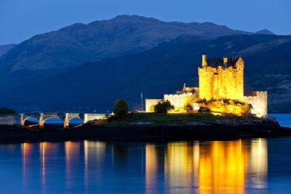 Eilean Donan Castle illuminated at night, reflecting on Loch Duich in Scotland